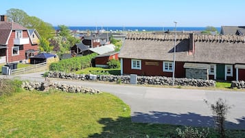 A coastal village with traditional houses, a stone wall, and a clear view of the sea.
