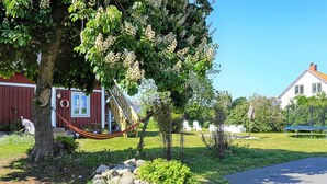 A garden with a hammock, a red barn, and a white house. - 6 Person Holiday Home in Solvesborg (Sölvesborg)