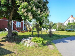 A garden with a hammock, a red barn, and a white house. - 6 Person Holiday Home in Solvesborg (Sölvesborg)