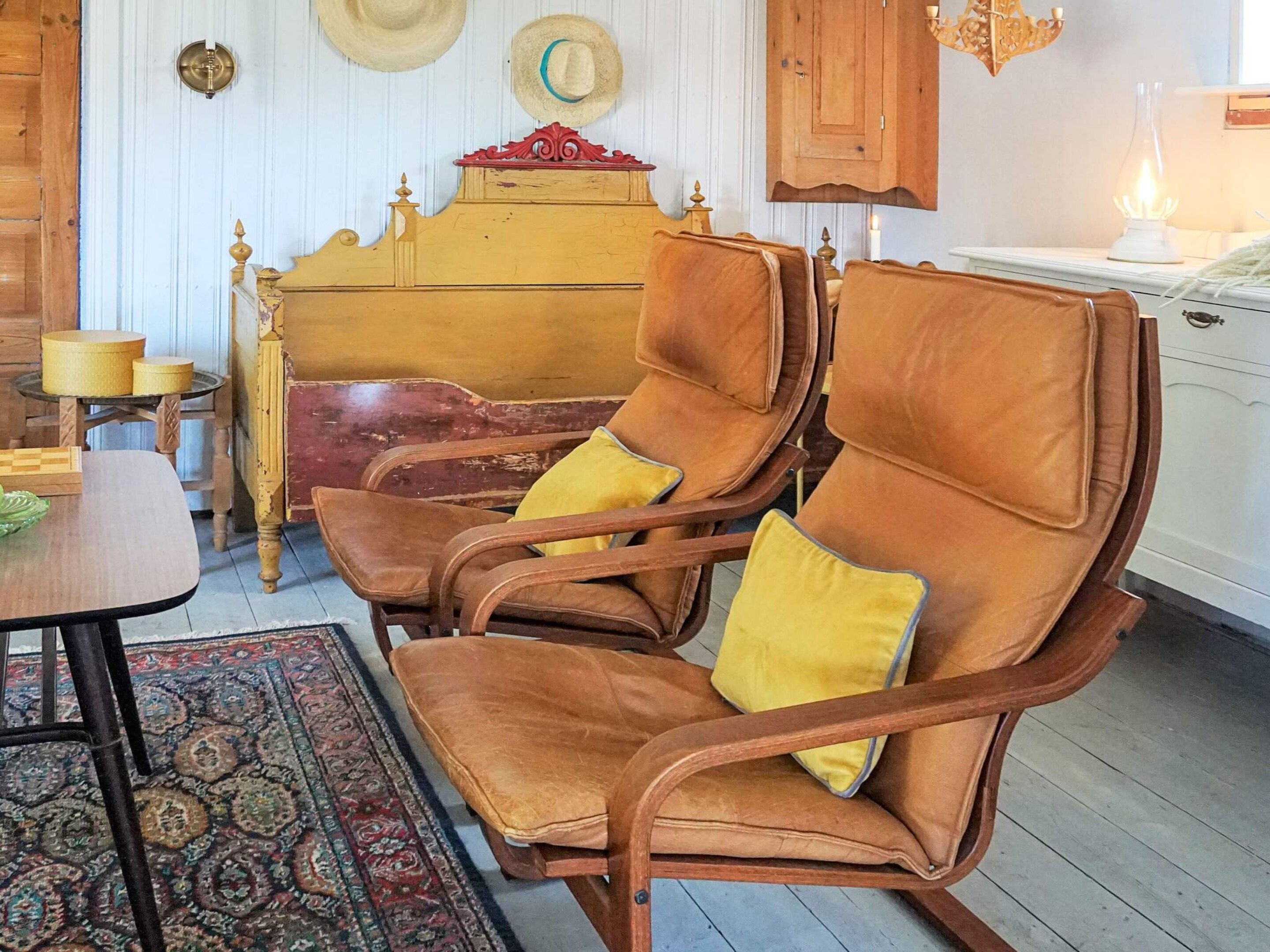A room with a wooden rocking chair, a small table, a patterned rug, and a wooden cabinet.