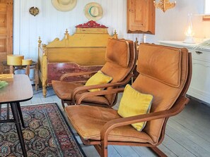 A room with a wooden rocking chair, a small table, a patterned rug, and a wooden cabinet. - 6 Person Holiday Home in Solvesborg (Sölvesborg)