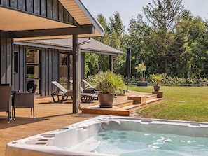Een modern buitengebied met een hottub, lounge stoelen en een overdekt terras.