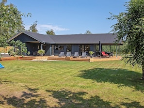 A modern house with a covered patio, a lawn, and a wooden deck. - 5 Star Holiday Home in Vaeggerlose (Vaeggerlose)