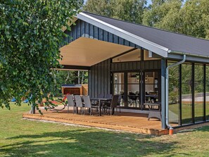 A modern outdoor patio with a dining area, a covered seating area, and a view of the surrounding landscape. - 5 Star Holiday Home in Vaeggerlose (Vaeggerlose)