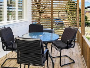 An outdoor patio with a round glass table and four chairs.