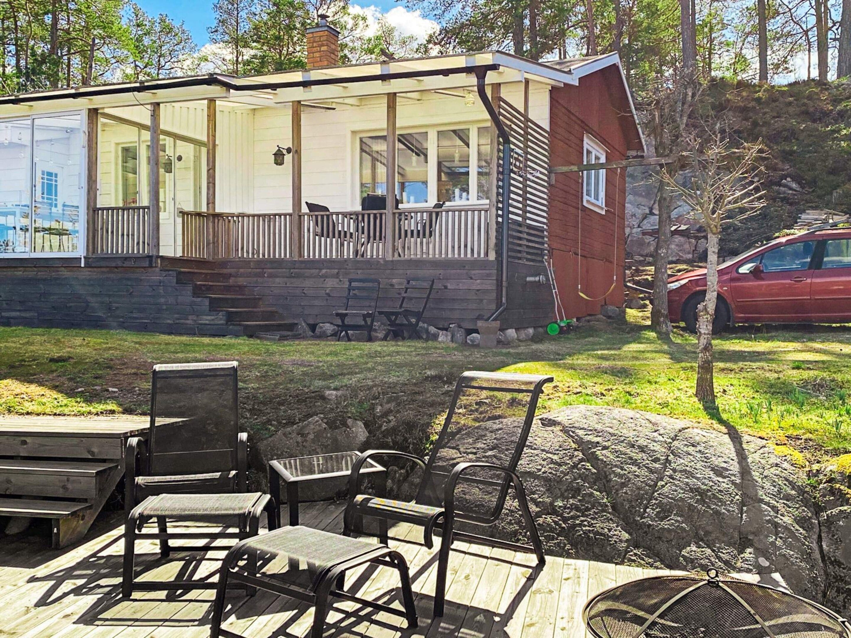 A cabin with a covered porch, outdoor seating, and a car parked nearby.