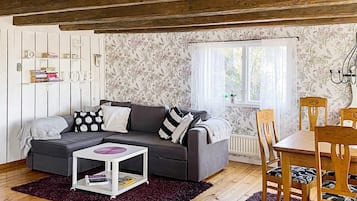 Una sala de estar acogedora con un sofá gris, una mesita blanca y una zona de comedor con sillas de madera y una mesa.