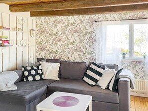 A living room with a grey sofa, patterned cushions, a white coffee table, and floral wallpaper.