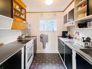 A compact kitchen with a microwave, stove, and various storage shelves.