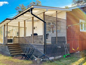 A covered outdoor area with a wooden deck, a basketball hoop, and a swing set. - 4 Star Holiday Home in Figeholm (Figeholm)