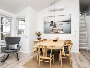 A dining area with a table, chairs, a vase, and a painting on the wall.