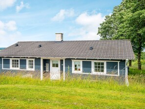 A single-story house with a dark blue exterior, a grey tiled roof, and white-framed windows. - 4 Star Holiday Home in Aabenraa (Aabenraa)
