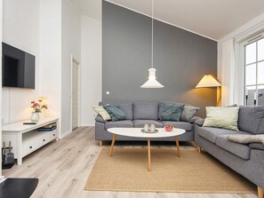 A modern living room with a grey sofa, a white coffee table, and a television mounted on the wall. - 4 Star Holiday Home in Aabenraa (Aabenraa)