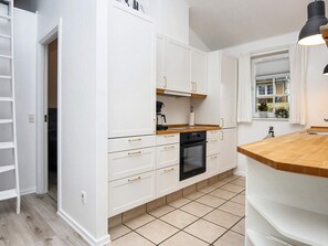 A kitchen with white cabinets, a black oven, and a wooden countertop. - 4 Star Holiday Home in Aabenraa (Aabenraa)