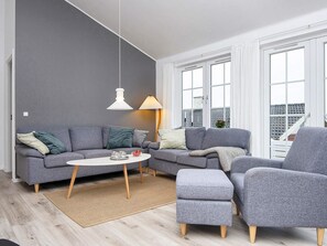 A modern living room with a grey sofa, a round coffee table, and a grey armchair.