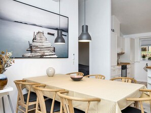 A dining area with a long table, chairs, a vase with dried flowers, a bowl, and a pendant light. - 4 Star Holiday Home in Aabenraa (Aabenraa)