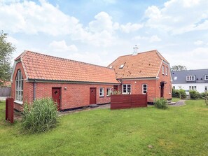 A two-story brick house with a red-tiled roof, a large window, and a wooden fence. - 6 Person Holiday Home in Albaek (Aalbaek)