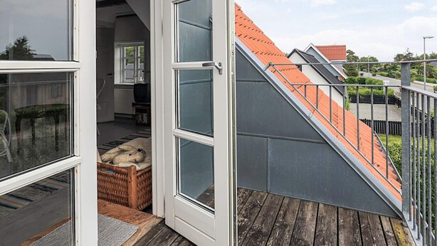 Un interno moderno con una scala che conduce a un balcone, un cesto di vimini e una televisione sullo sfondo.
