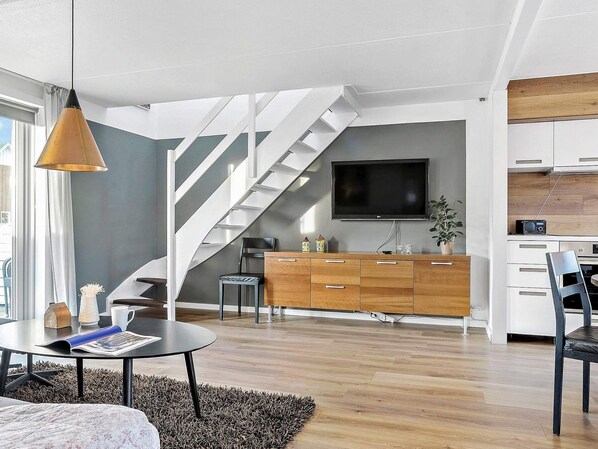 A modern living room with a staircase, a flat-screen TV, a wooden cabinet, and a dining area. - 4 Star Holiday Home in Romo (Rømø)