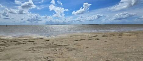 A beach with footprints, a clear sky, and a calm sea.