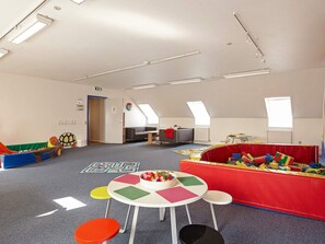 A children's playroom with a play area, tables, and a sofa.