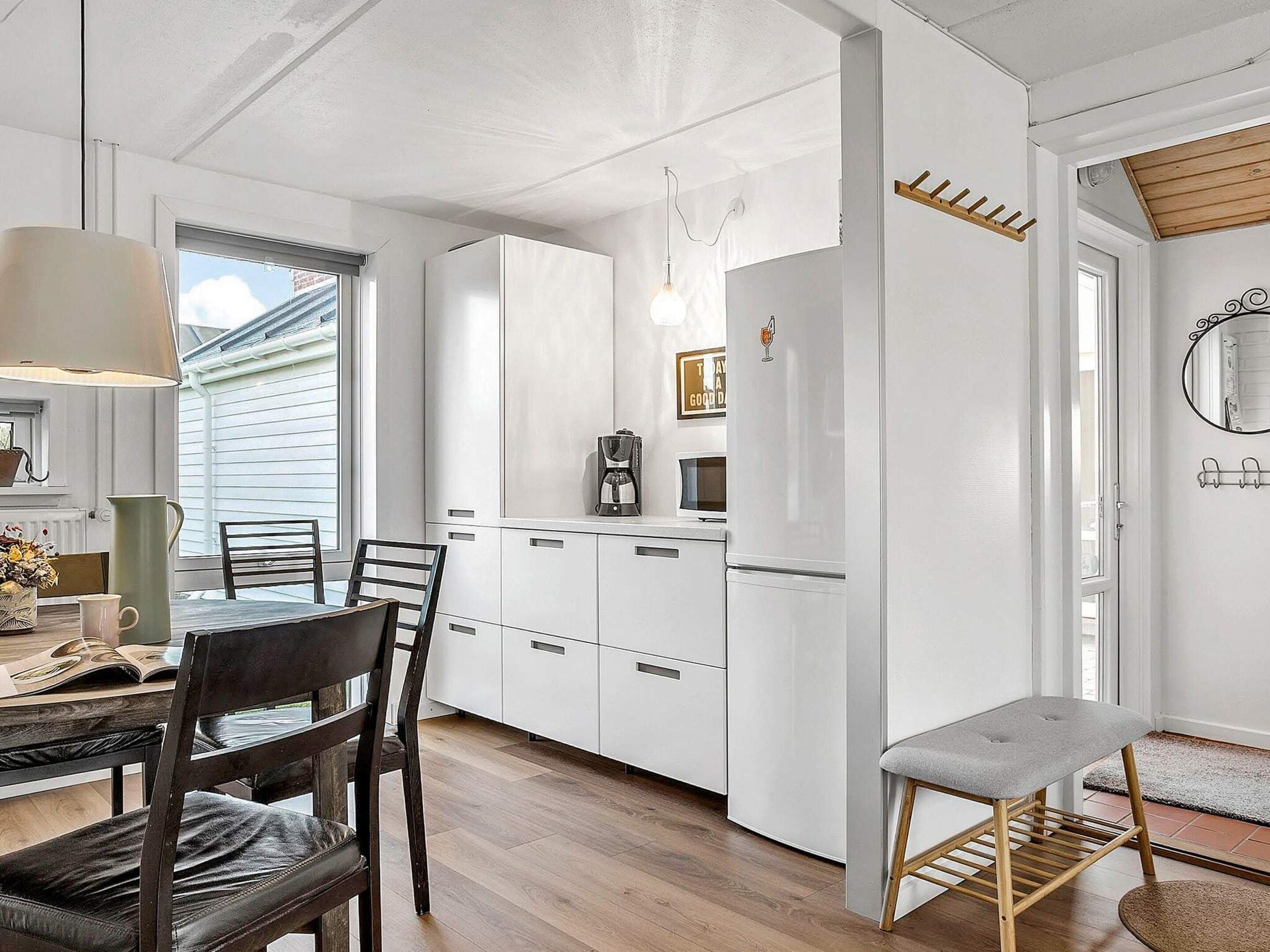 A modern kitchen with white cabinetry, a coffee maker, and a refrigerator.