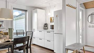 A modern kitchen with white cabinetry, a coffee maker, and a refrigerator.