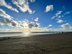 A beach with a clear sky and footprints in the sand.
