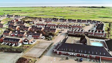 A residential area with multiple red-roofed houses arranged in rows, a large parking area, and a swimming pool.