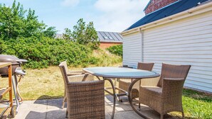 An outdoor patio with wicker furniture and a barbecue grill.
