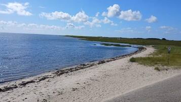 A coastal road with a sandy beach and a clear blue sky.