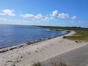 A coastal road with a sandy beach and a clear blue sky.