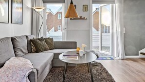 A modern living room with a grey sofa, a round coffee table, and a hanging pendant lamp.