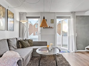 A modern living room with a grey sofa, a round coffee table, and a hanging pendant lamp.