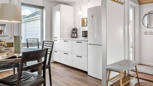 A modern kitchen with white cabinetry, a coffee machine, and a dining area with a table and chairs.