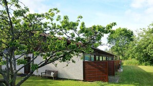Ein modernes Haus mit weißer Fassade, einem Holzzaun und einer Bank im Garten.