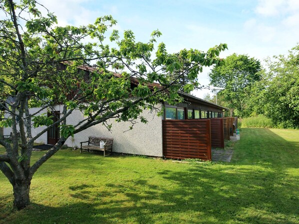 Une maison moderne avec une façade blanche, une clôture en bois et un banc dans la cour.