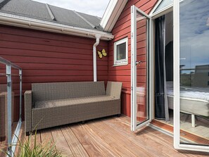 A red exterior wall with a sliding glass door leading to a balcony with a wicker sofa. - 6 Person Holiday Home in Hadsund (Hadsund)