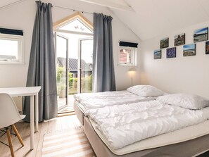 A bedroom with a bed, a desk, and a balcony with curtains. - 6 Person Holiday Home in Hadsund (Hadsund)