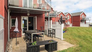 A red building with a balcony, outdoor seating, and a grassy yard. - 6 Person Holiday Home in Hadsund (Hadsund)