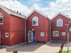 A red wooden building with a central door and two windows on the upper floor. - 6 Person Holiday Home in Hadsund (Hadsund)