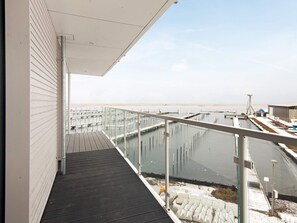 A balcony with a view of a water body and industrial structures. - 5 Star Holiday Home in Wendtorf (Wendtorf)