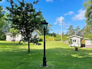 A well-maintained grassy area with a lamp post, two small cabins, and a clear blue sky.