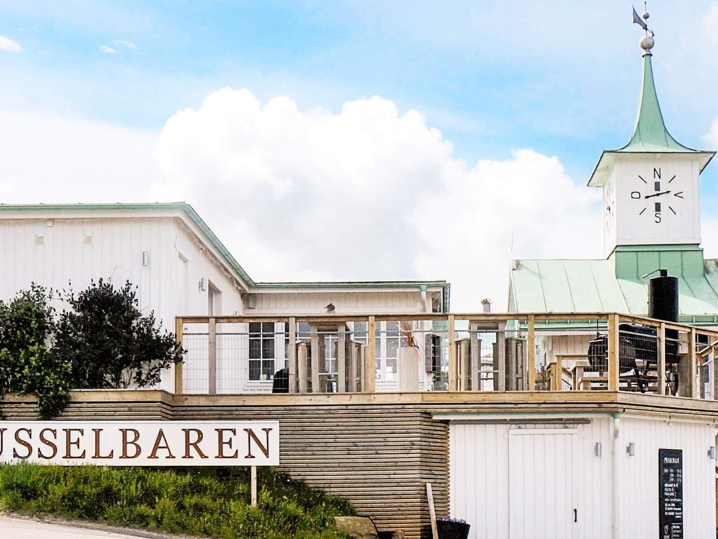 Een gebouw met een bord waarop 'VUSSELBAREN' staat en een klokkentoren.