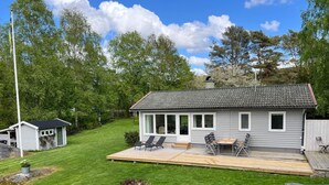 A house with a deck, a small shed, and a garden with flowers. - 4 Star Holiday Home in Ljungskile (Ljungskile)