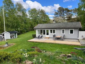 A house with a deck, a small shed, and a garden with flowers. - 4 Star Holiday Home in Ljungskile (Ljungskile)