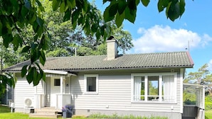 A single-story house with a front porch, a chimney, and a small garden area. - 4 Star Holiday Home in Ljungskile (Ljungskile)