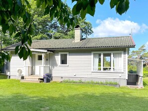 A single-story house with a front porch, a chimney, and a small garden area. - 4 Star Holiday Home in Ljungskile (Ljungskile)