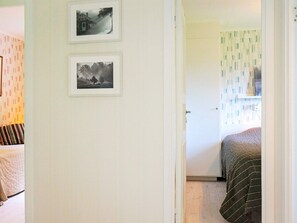 A room with a bed, a door leading to another room, and two framed pictures on the wall.