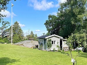 A small house with a sloped roof, surrounded by a well-maintained lawn and trees.